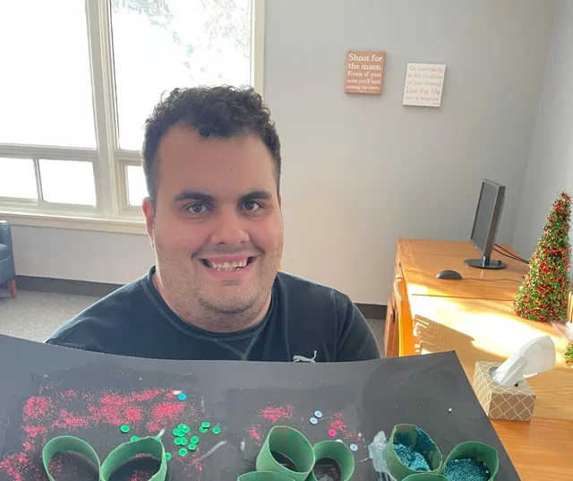 Participant holding up art he's made in a Respite program.