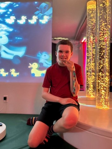 Boy in a sensory play area smiling.