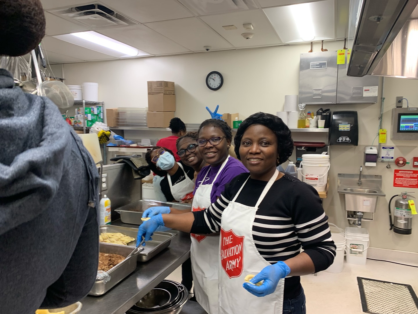 a group of female volunteers helping out in the kitchen, all wearing the salvation army apron