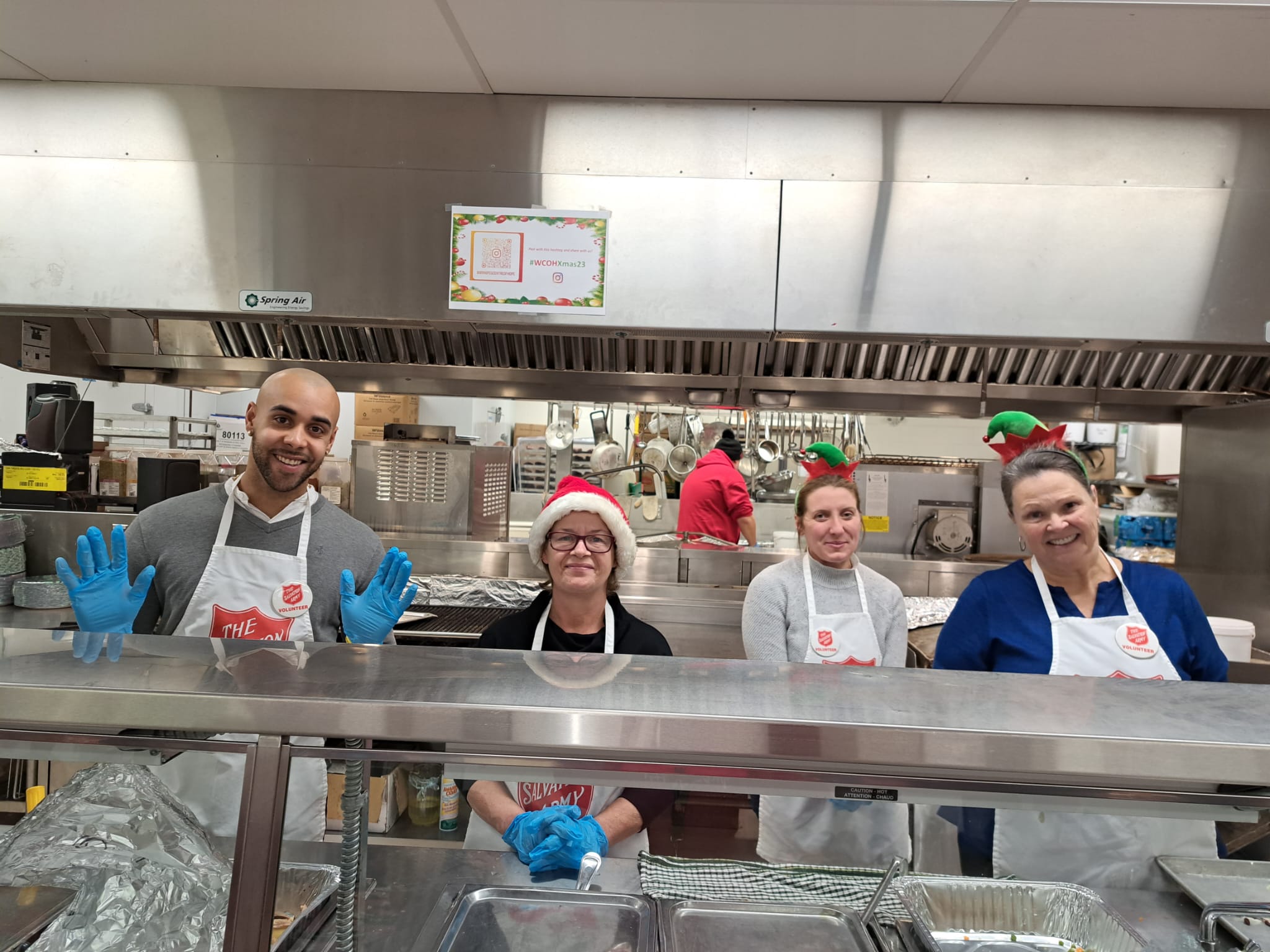 a group of volunteers helping out in the kitchen, all wearing the salvation army apron