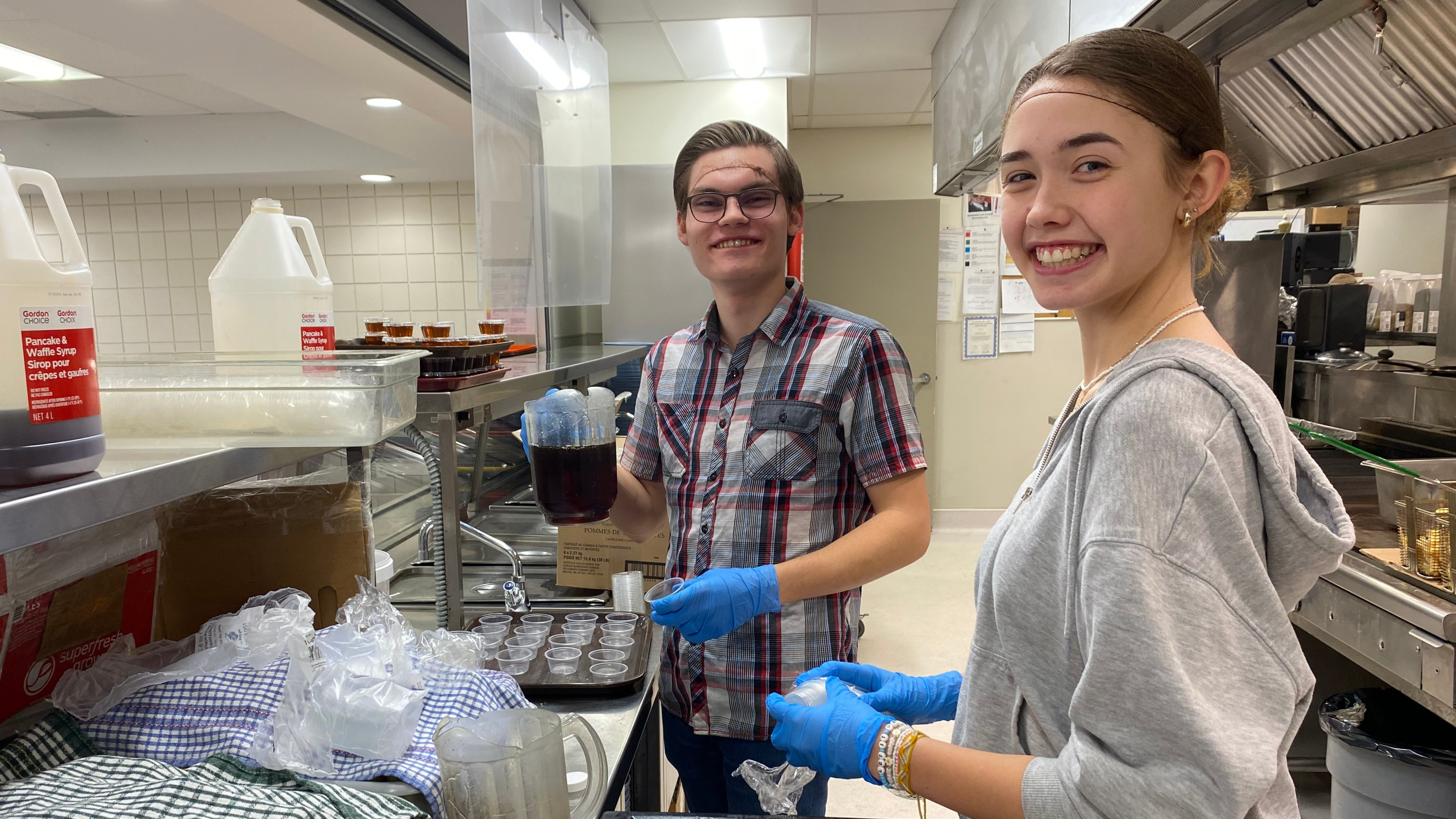 2 volunteers (male and female) helping out in the kitchen